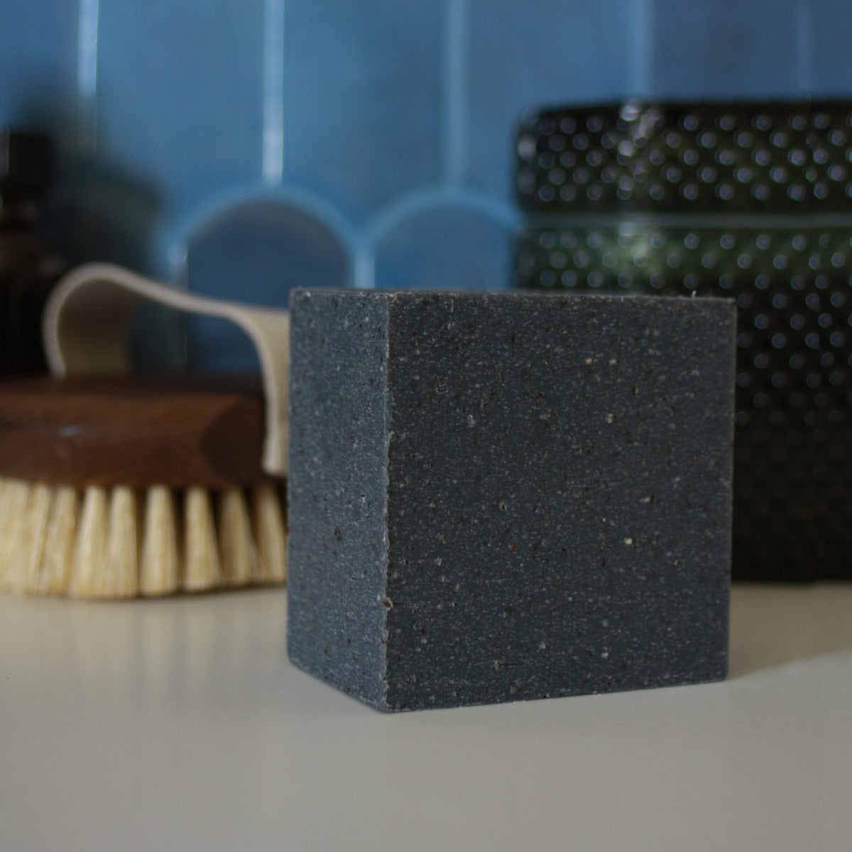 dark grey speckled block of soap against blue stylized tile backdrop
