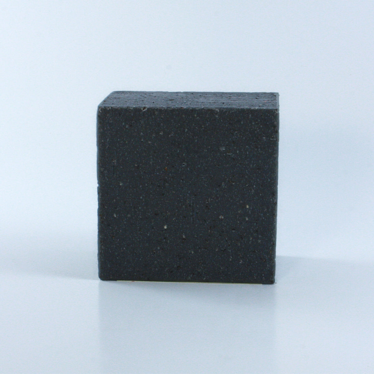 Concrete + Clay Unscented Exfoliating Hand Soap with a black speckled and heavily textured finish and clean rectangular shape photographed from the front on a neutral background.