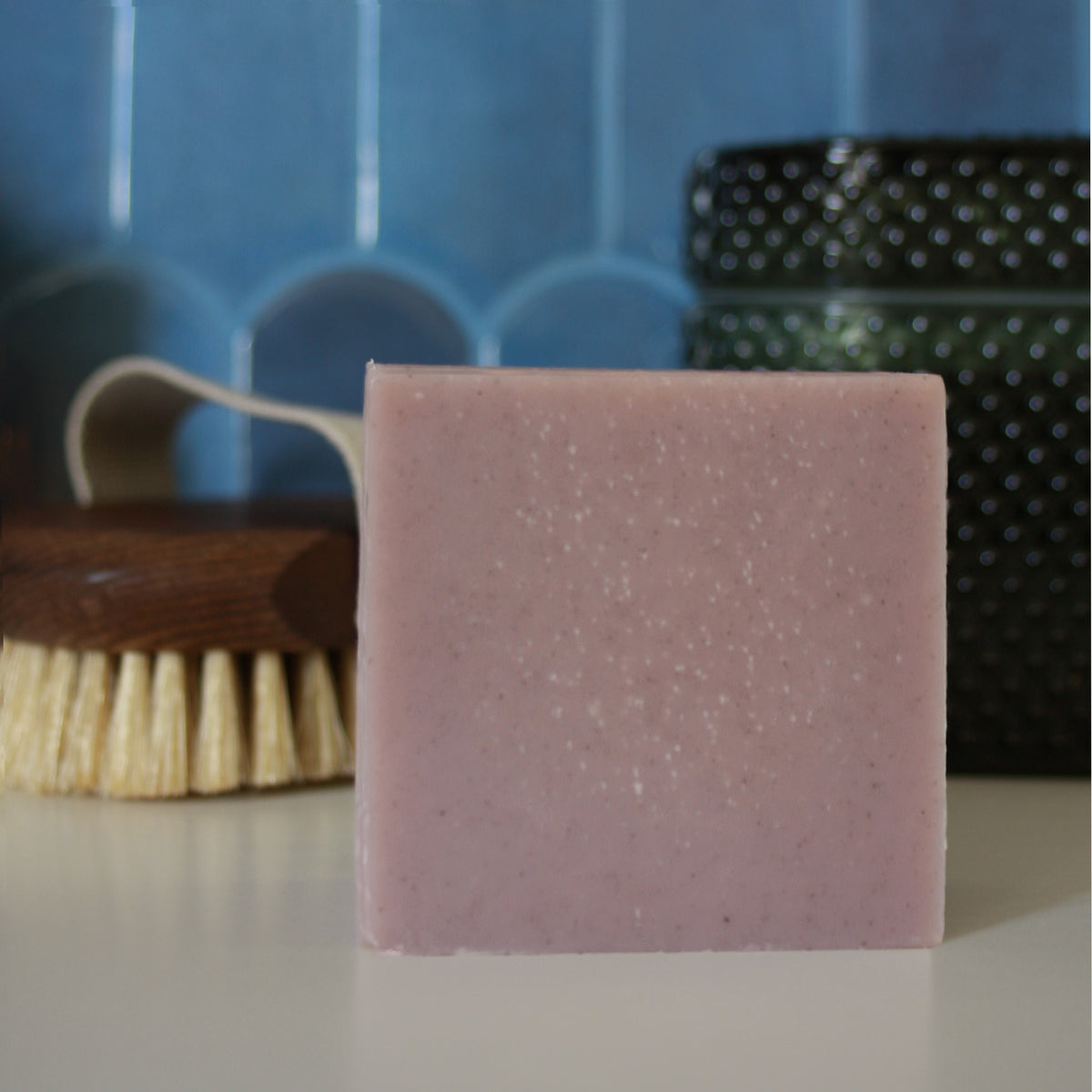 light earthy purple block of soap against stylized blue tile background