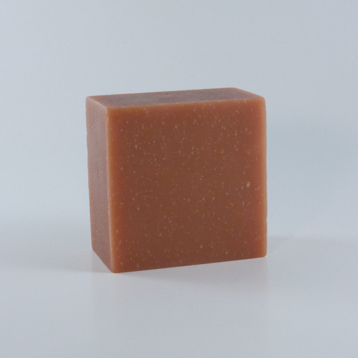 Resistance Rose Geranium + Sandalwood Soap with an orange pink finish and clean rectangular shape photographed from an angle on a neutral background.