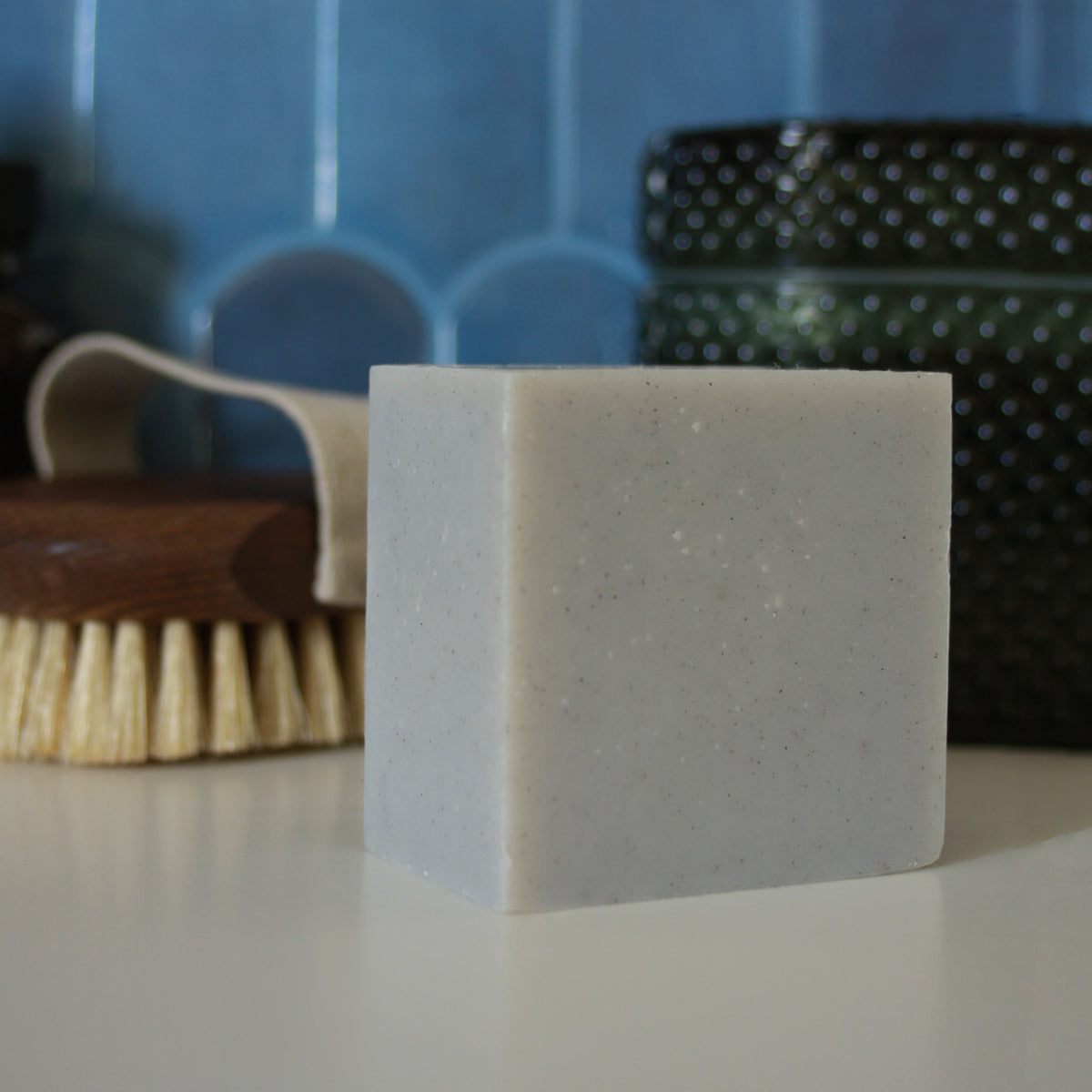 grayish blue block of soap against blue tile stylized background