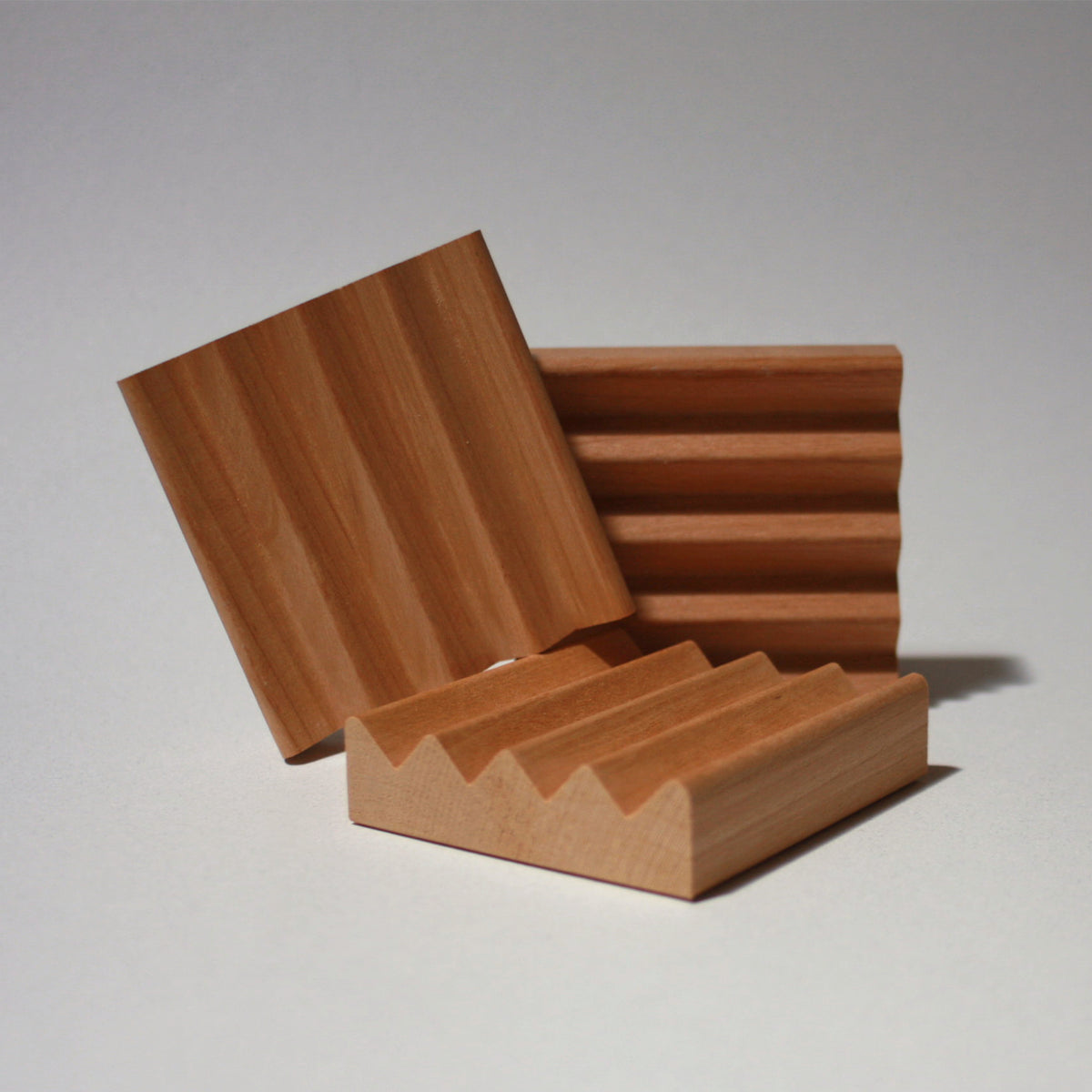 Three small wooden dishes with grooved zig-zag surface, shown on a plain light gray studio background.